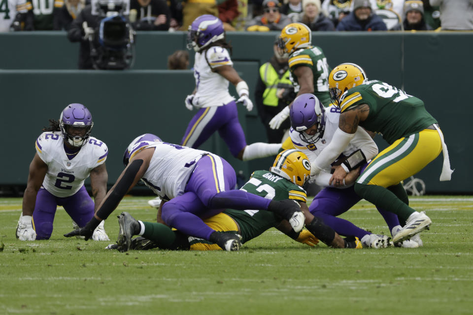 Minnesota Vikings quarterback Kirk Cousins (8) is tackled by Green Bay Packers linebacker Rashan Gary (52), middle left, and linebacker Preston Smith (91), right, during the second half of an NFL football game Sunday, Oct. 29, 2023, in Green Bay, Wis. (AP Photo/Mike Roemer)