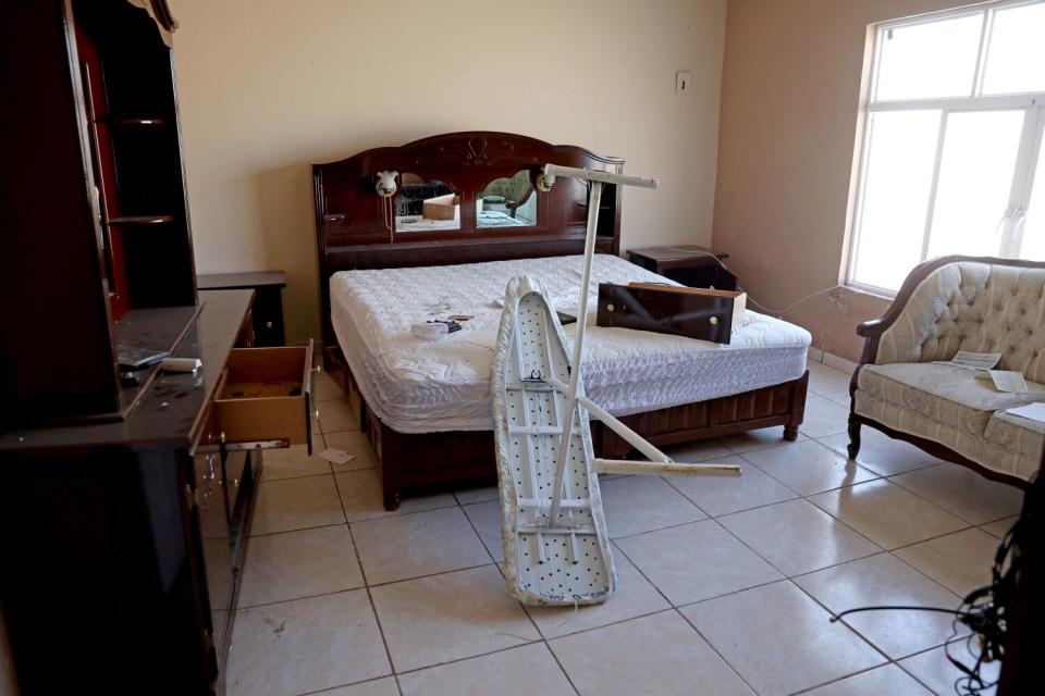 A room with a stripped bed, an overturned ironing board and an empty drawer