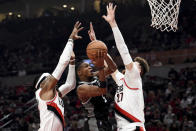 Sacramento Kings guard De'Aaron Fox, center, drives to the basket on Portland Trail Blazers forward Robert Covington, left, and center Jusuf Nurkic during the first half of an NBA basketball game in Portland, Ore., Wednesday, Oct. 20, 2021. (AP Photo/Steve Dykes)