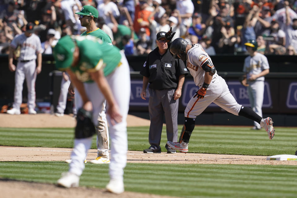 San Francisco Giants' Donovan Solano, right, rounds the bases after hitting a two-run home run off of Oakland Athletics pitcher A.J. Puk, left, during the eighth inning of a baseball game in Oakland, Calif., Sunday, Aug. 22, 2021. (AP Photo/Jeff Chiu)