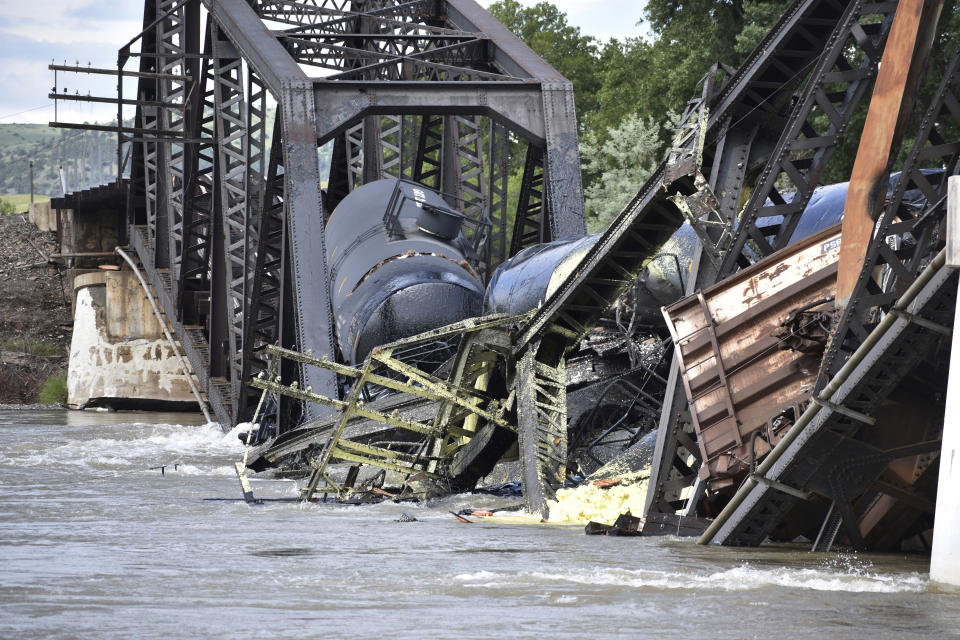 Several train cars are immersed in the Yellowstone River after a bridge collapse near Columbus, Mont., on Saturday, June 24, 2023. The bridge collapsed overnight, causing a train that was traveling over it to plunge into the water below. Authorities on Sunday were testing the water quality along a stretch of the Yellowstone River where mangled cars carrying hazardous materials remained after crashing into the waterway. (AP Photo/Matthew Brown)