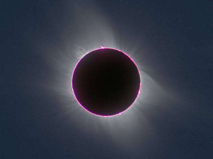 total solar eclipse shows dark circle of moon's shadow with purple ring around it where the sun is hiding