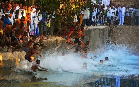 Ethiopian Orthodox pilgrims jump into the Fasilides baths during the Timkat - Credit: Getty