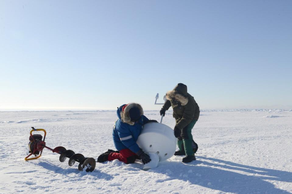A research team deploys an ice beacon — a tool with sensors that measure GPS position, ice thickness, temperatures and other parameters — on sea ice in northern Alaska. <cite>Ignatius Rigor/Polar Science Center, Applied Physics Laboratory, University of Washington</cite>