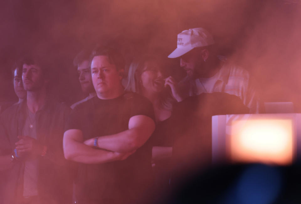 Group of people in dim lighting, Travis and Taylor looking at each other and her smiling