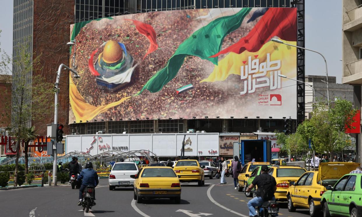 <span>Iranians drive down a street next to a pro-Palestine poster in Tehran.</span><span>Photograph: Atta Kenare/AFP/Getty</span>