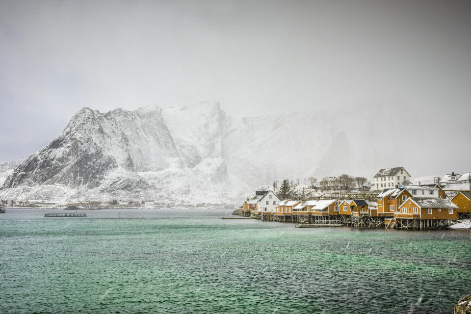 Snowy mountains overlooking the rocky coastline in Reine, Lofoten Islands