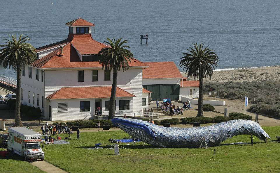 FILE - In this Oct. 12, 2018, file photo, artist Joel Deal Stockdill, lower right, works on a blue whale art piece made from discarded single-use plastic at Crissy Field in San Francisco. Artists were putting the finishing touches on the 82-foot-long (24-meter-long) blue whale made from discarded plastic that will be in display near San Francisco's Golden Gate Bridge to raise awareness about ocean pollution. (AP Photo/Eric Risberg, File)