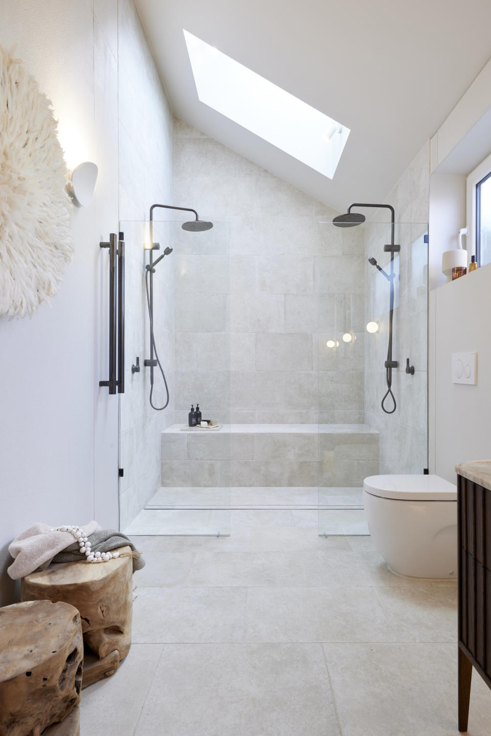 A shot of the double shower, with two wooden seats on the bottom left. 