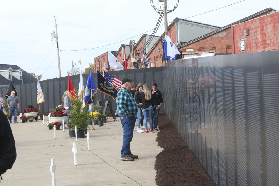 Visitors look over the traveling Vietnam Wall on display through Sunday at the New Philadelphia.