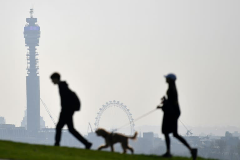 Dos personas pasean por Primrose Hill, en Londres, con la Torre BT y la noria London Eye de fondo, el 24 de marzo de 2022 (Justin Tallis)