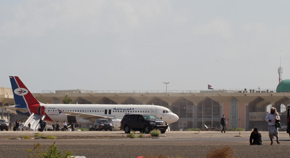 Bystanders stand near the runway of Yemen southern city of Aden's airport shortly after an explosion hit as a government plane landed, Wednesday, Dec. 30, 2020. The blast struck the airport building shortly after a Yemenia airlines plane carrying the newly formed Cabinet landed. No one on the government plane was hurt. (AP Photo/Wael Qubady)