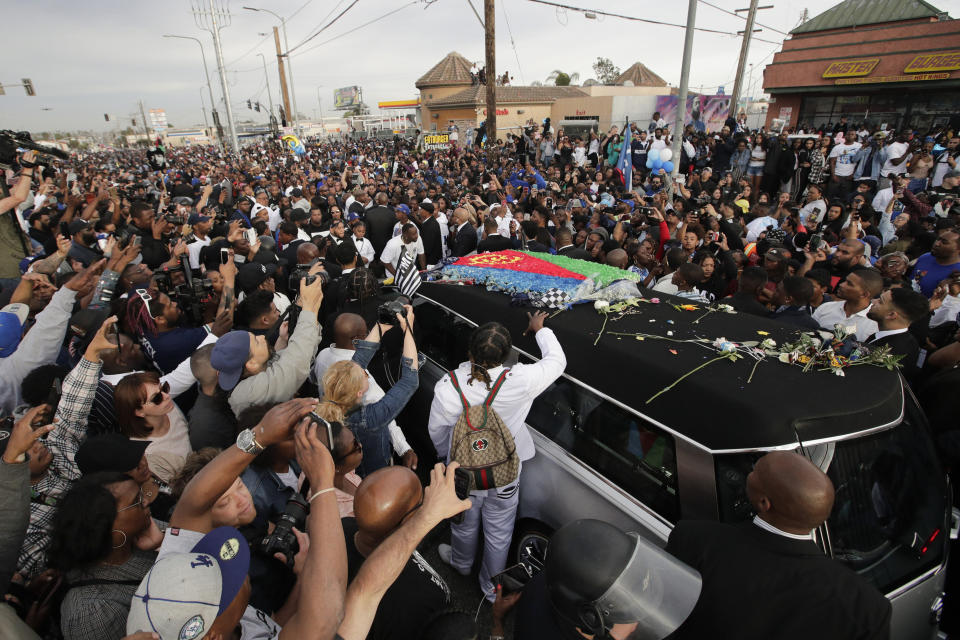 A hearse carrying the casket of slain rapper Nipsey Hussle, draped in the flag of his father’s native country, Eritrea in East Africa, passes through the crowd Thursday, April 11, 2019, in Los Angeles. Hussle was shot to death March 31 while standing outside The Marathon, his South Los Angeles clothing store, not far from where the rapper grew up. (AP Photo/Jae C. Hong)
