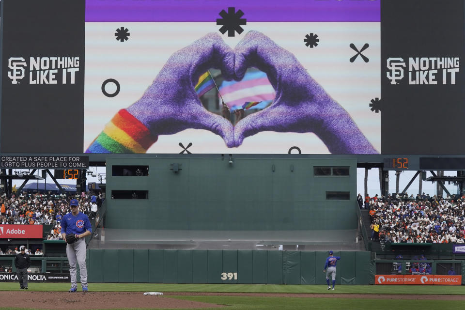 A image for the Pride Parade is displayed on the video board during San Francisco Giants' Pride Day as Chicago Cubs pitcher Kyle Hendricks, bottom, warms up during the third inning of a baseball game between the Giants and the Chicago Cubs in San Francisco, Saturday, June 10, 2023. (AP Photo/Jeff Chiu)