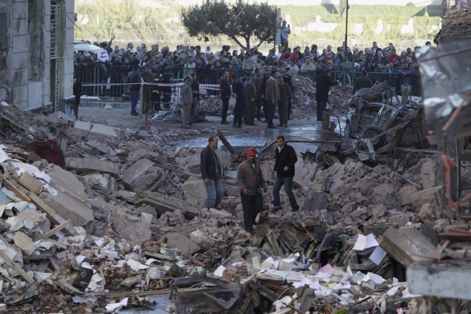 People walk near debris after an explosion near a security building in Egypt's Nile Delta town of Dakahlyia