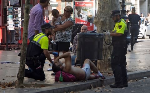 Police speak to an injured person at the scene. Local media report the van driver ran away