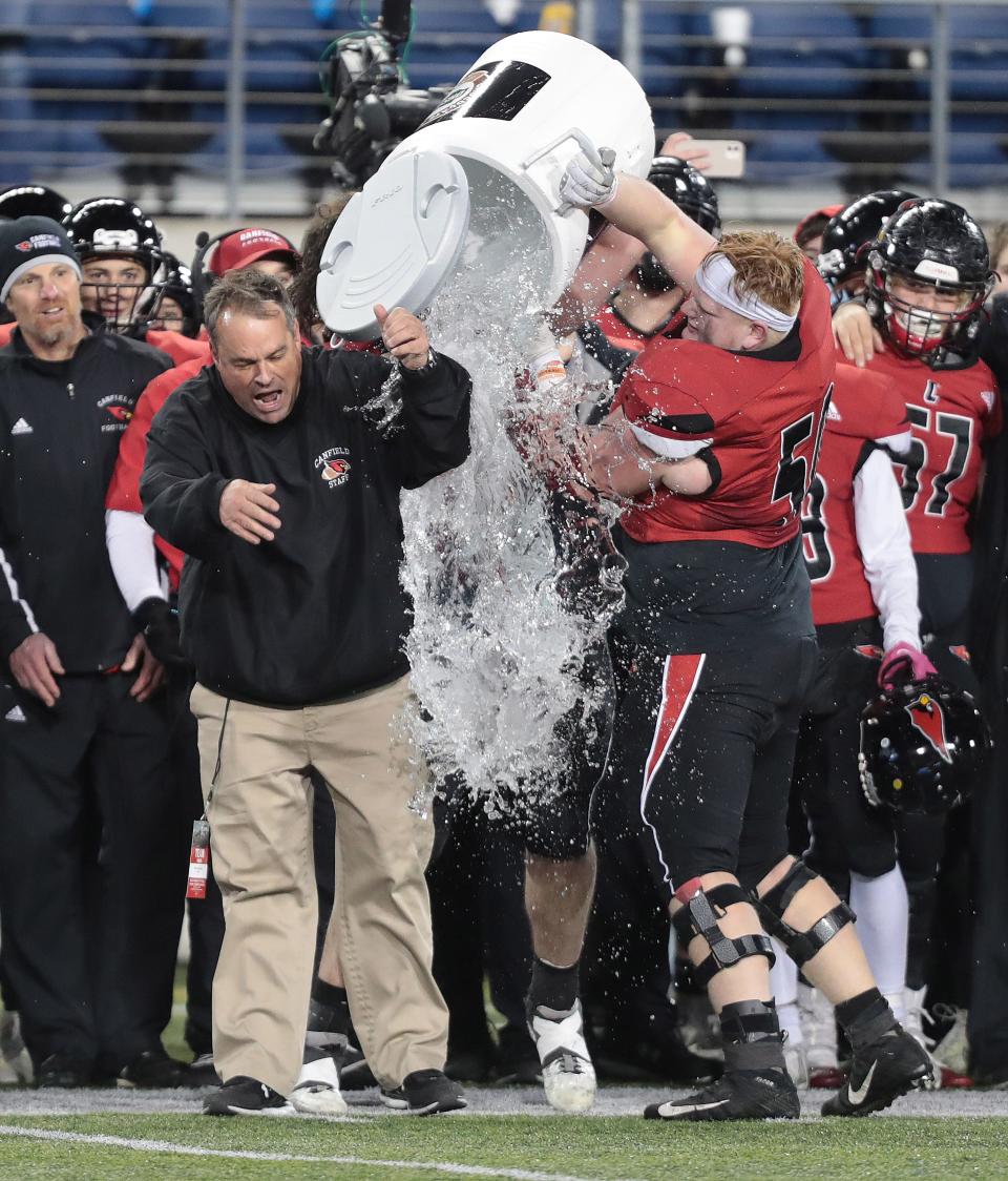 Canfield head coach Michael Pavlansky gets drenched by his players as the last seconds tick off the clock in their win over Bloom-Carroll in the Division III state final at Tom Benson Hall of Fame Stadium in Canton, Friday, Dec. 2, 2022.