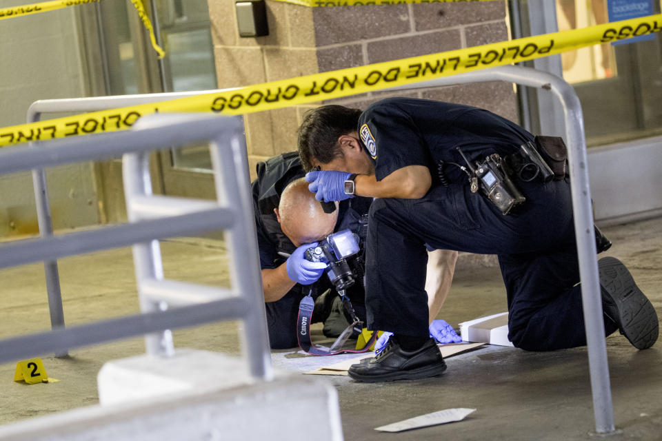 Police officers photograph bullets and a firearm magazine at a crime scene following a shooting at the parking garage for the Fashion Centre at Pentagon City, also known as Pentagon City Mall, Monday, July 1, 2019, in Arlington. (AP Photo/Andrew Harnik)