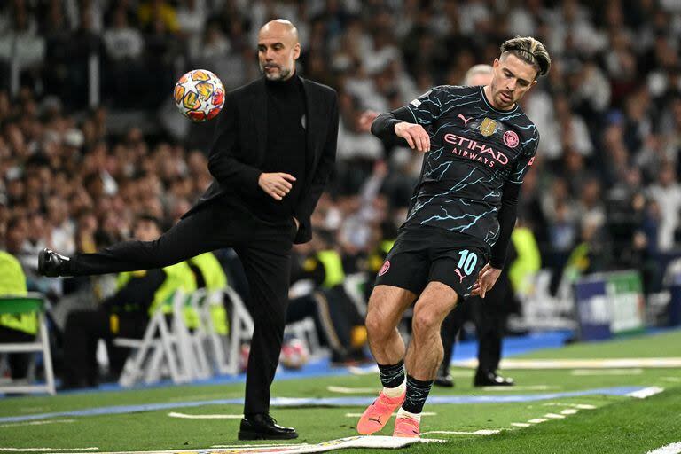 Manchester City's Spanish manager Pep Guardiola (L) controls the ball at the touchline during the UEFA Champions League quarter final first leg football match between Real Madrid CF and Manchester City at the Santiago Bernabeu stadium in Madrid on April 9, 2024. (Photo by JAVIER SORIANO / AFP)