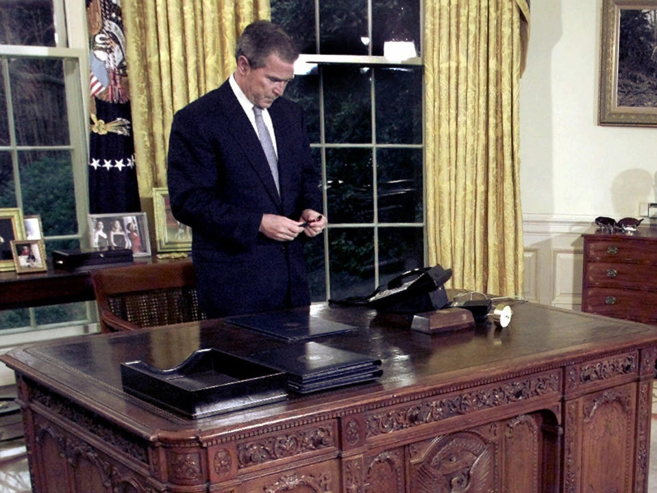 El presidente George W. Bush en su escritorio en la Oficina Oval. El botón especial se ve allí también junto al teléfono. (AP Photo/Ron Edmonds, File)