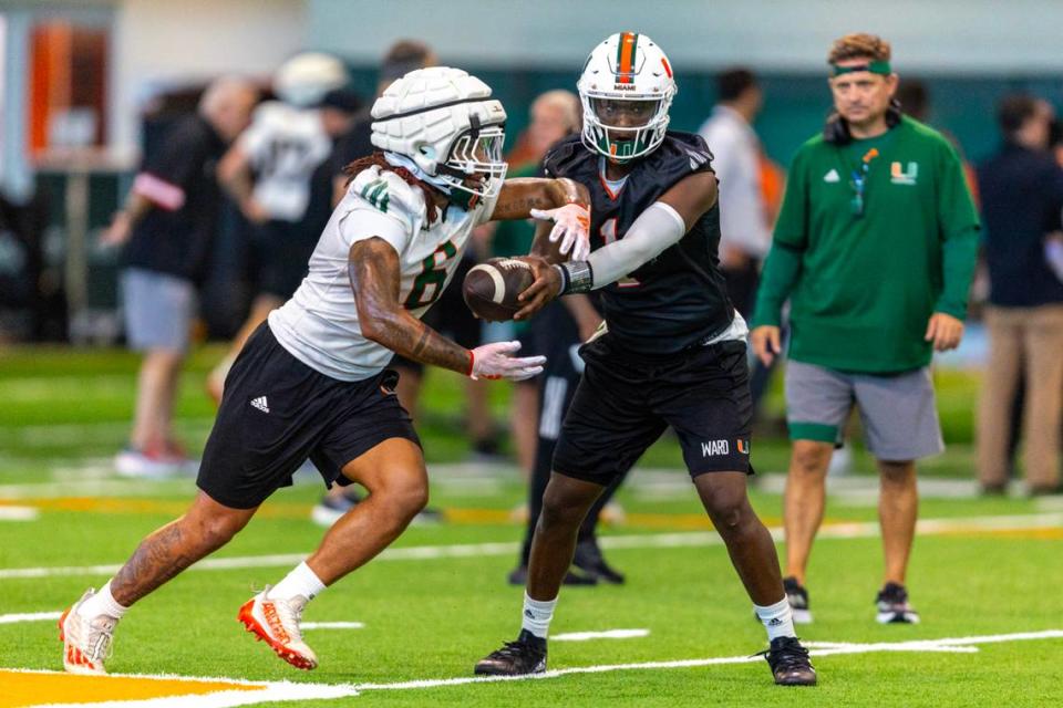 Miami Hurricanes quarterback Cam Ward (1) hands off the ball to running back Damien Martinez (6) during practice at the Carol Soffer Indoor Practice Facility on Thursday, August 1, 2024, in Coral Gables, Fla.