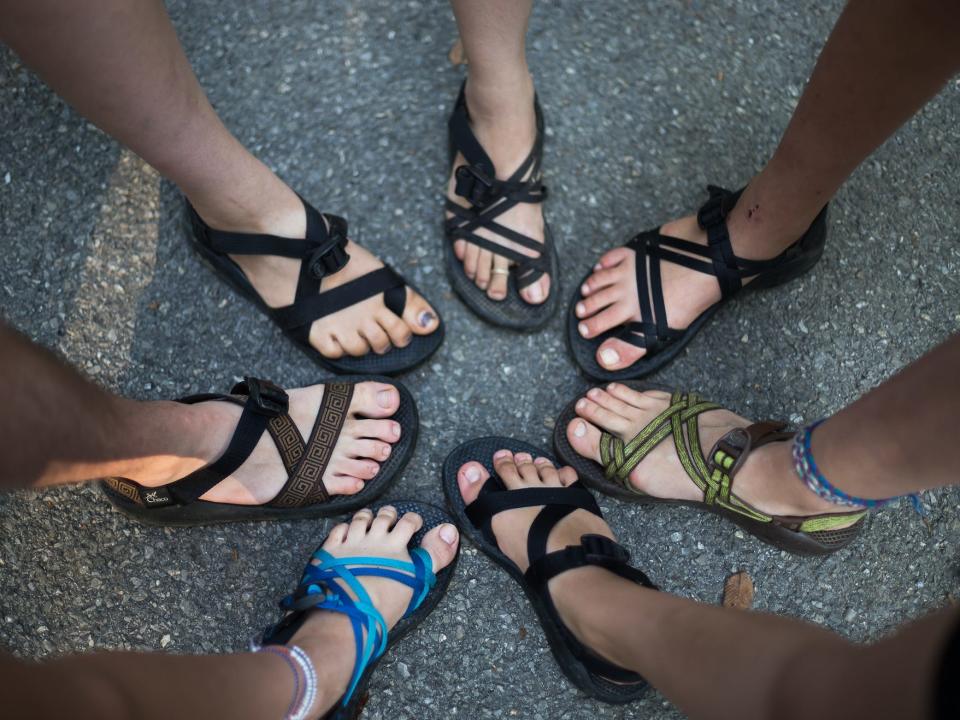 feet in a circle all wearing sporty water sandals