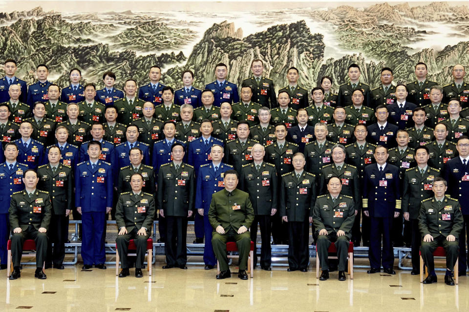 In this photo released by Xinhua News Agency, Chinese President Xi Jinping, bottom center, also general secretary of the Communist Party of China Central Committee and chairman of the Central Military Commission, poses for a group photo with deputies from the delegation of the People's Liberation Army (PLA) and the People's Armed Police Force before attending a plenary meeting of the delegation during the first session of the 14th National People's Congress (NPC) in Beijing, on Wednesday, March 8, 2023. Xi has called for "more quickly elevating the armed forces to world-class standards," in a speech coming days after he warned the country was threatened by a U.S.-led campaign of "containment, encirclement and suppression of China." (Li Gang/Xinhua via AP)