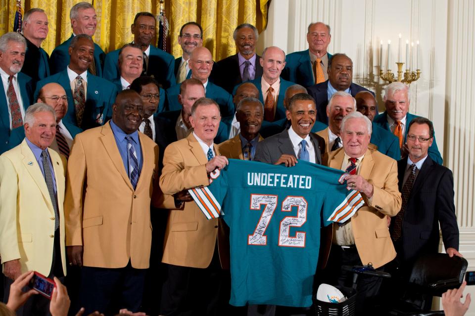 Former Miami Dolphin's quarterback Bob Griese, left, holds a signed jersey with President Barack Obama and Hall of Fame coach Don Shula, 41 years after their perfect football season as the Super Bowl VII Champions were honored in the East Room of the White House in Washington on Aug. 20, 2013.