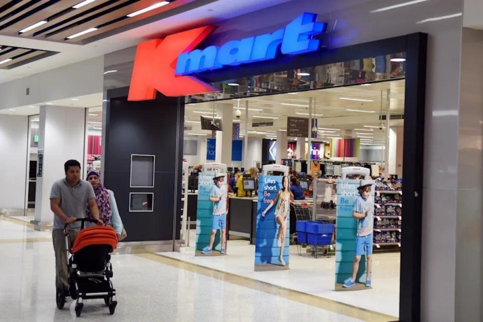 Couple with stroller walks past open Kmart store