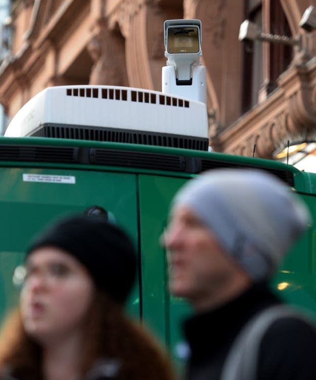 A white camera mounted on the roof of a green van. 