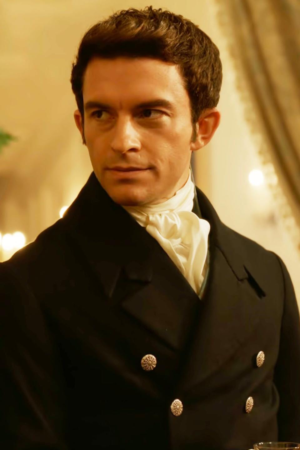 Jonathan Bailey as Anthony Bridgerton, wearing a dark-tailored suit with a cravat