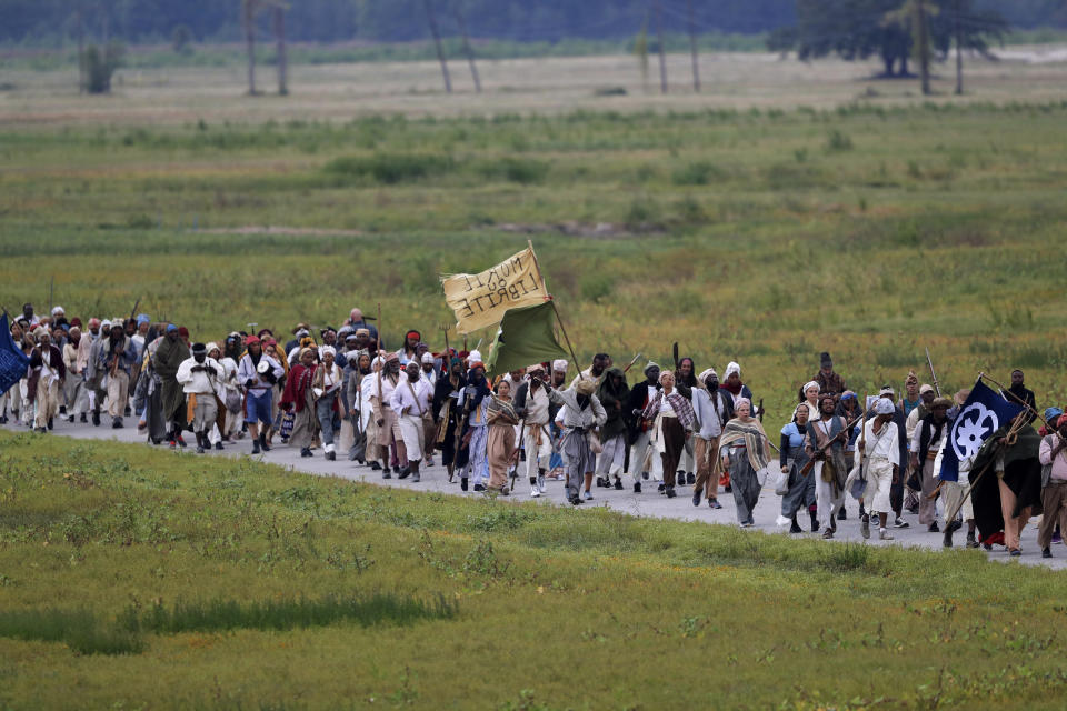 People march through the Bonnet Carre Spillway as they participate in a performance artwork reenacting the largest slave rebellion in U.S. history, in Norco, La., Friday, Nov. 8, 2019. The reenactment was conceived by Dread Scott, an artist who often tackles issues of racial oppression and injustice. (AP Photo/Gerald Herbert)