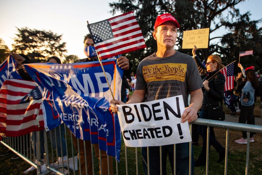 BEVERLY HILLS, CA - NOVEMBER 07: A Trump supporter somberly holds a Biden Cheated sign at a Trump rally in Beverly Hills as Joe Biden is elected president on Saturday, Nov. 7, 2020 in Beverly Hills, CA. (Jason Armond / Los Angeles Times)