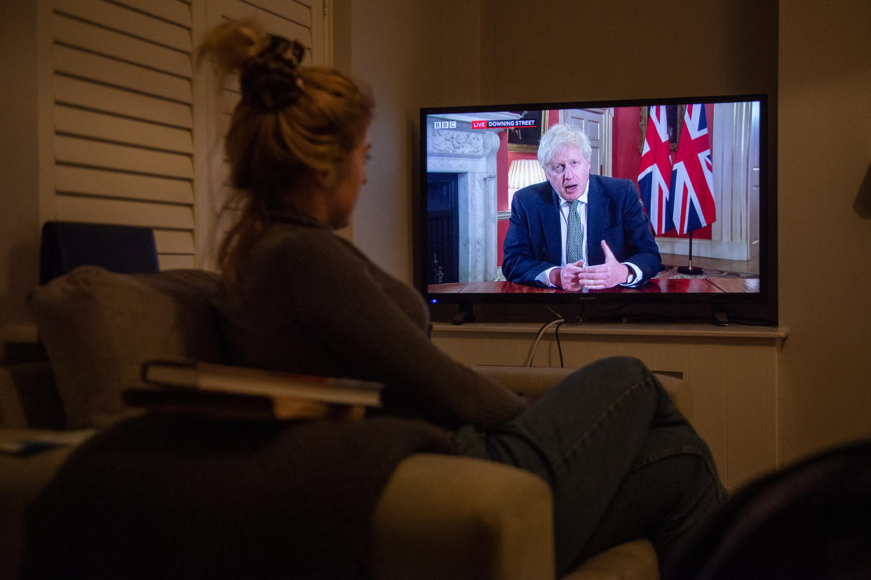 A woman watches Prime Minister Boris Johnson making a televised address to the nation from 10 Downing Street, London, setting out new emergency measures to control the spread of coronavirus in England.