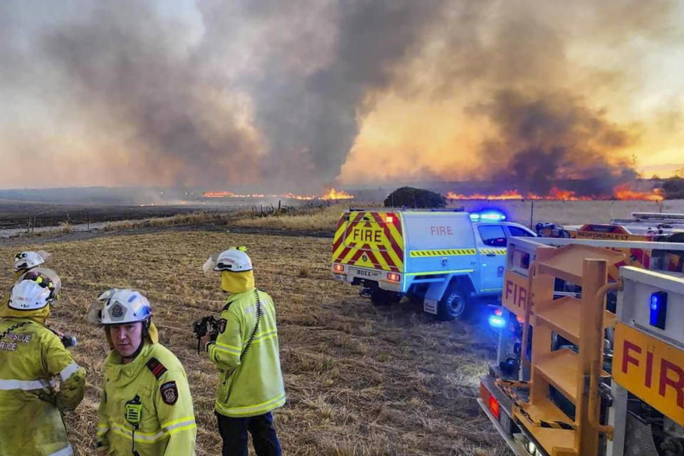 West Australian firefighters watch as grassland burns near the West Australian city of Wannaroo, north of Perth in the early hours of Thursday, Nov. 23, 2023. Dozens of residents have been evacuated and at least 10 homes have been destroyed by a wildfire that is burning out of control on the northern fringe of the west coast city of Perth during heatwave spring conditions, authorities say.(DFES via AP)