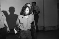 <p>Charles M. Manson, squinting in the glare of a film cameraman’s floodlight, marches to court, Aug. 20, 1970, for a hearing on his claim that he is being mistreated by deputies in the Los Angeles County Jail. After the hearing, his trial on murder charges resulting from the slayings of actress Sharon Tate and six other people was scheduled to resume. (Photo: George Brich/AP) </p>