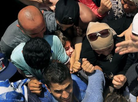 A Syrian refugee girl is squashed as other clash during registration procedure in the national stadium of the Greek island of Kos August 11, 2015. REUTERS/ Yannis Behrakis