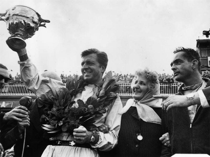 Wolfgang von Trips driver of the winning Ferrari holds high his trophy after the 1961 British Grand Prix at Aintree, Liverpool. On the right is Phil Hill who came second in another Ferrari.
