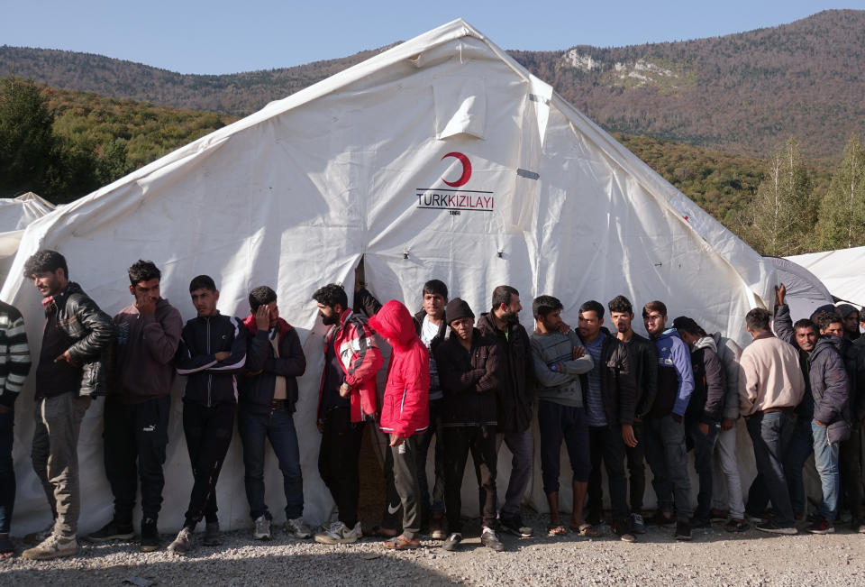 Migrants wait in line to receive supplies from the Red Cross at the Vucijak refugee camp outside Bihac, northwestern Bosnia, Monday, Oct. 21, 2019. Authorities in the town of Bihac on Monday stopped the delivery of water supplies to the Vucjak camp saying they want to draw attention to the problems in the camp set up on a former landfill and near mine fields from the 1992-95 war. (AP Photo/Eldar Emric)