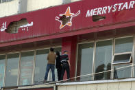 Chinese men examine damaged sign boards near the site of Wednesday's explosion outside the Urumqi South Railway Station in Urumqi in northwest China's Xinjiang Uygur Autonomous Region on Thursday, May 1, 2014. Chinese President Xi Jinping has demanded "decisive actions" against terrorism following an attack at the railway station in the far-west minority region of Xinjiang that left three people dead and 79 injured. (AP Photo/Ng Han Guan)