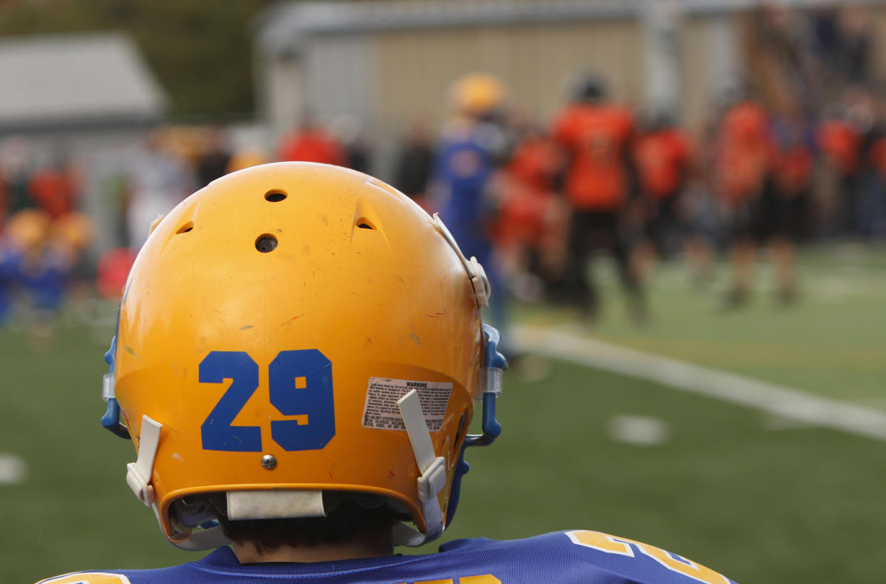 A football player watching his teammates on the field.