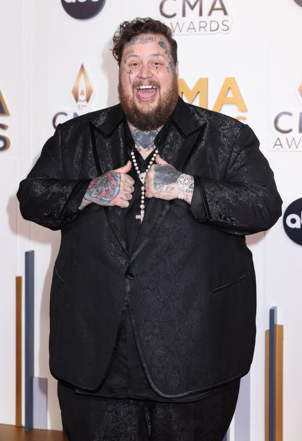 jelly roll holding the front of his suit and smiling upon his arrival at the cma awards