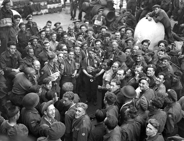 An unidentified Canadian soldier playing the bagpipes aboard a ship en route to France on D-Day, 6 June 1944.