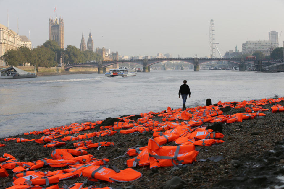 A man walks to pose for pictures among hundreds of lifejackets