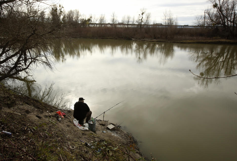 A fisherman sits along the slough where the body of an infant, Nikko Lee Perez, was discovered in Yolo County in 2007, near Woodland, California. (Photo: ASSOCIATED PRESS)