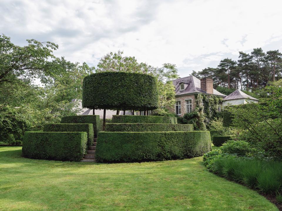 Celebrated Belgian landscape designer Jacques Wirtz designed the garden, with clipped hedges that provide contrast to romantic rambling vines and loosely arranged greenery. Neatly clipped edges direct the eye over unsightly water pumps used for irrigation and other domestic needs.