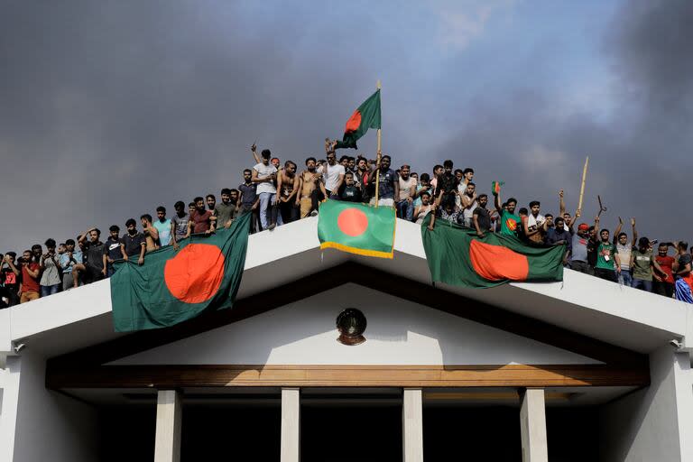 Manifestantes antigubernamentales muestran la bandera nacional de Bangladesh mientras irrumpen en el palacio de la primera ministra Sheikh Hasina en Dacca el 5 de agosto de 2024. 