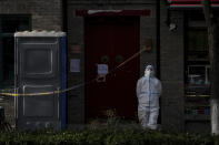 A worker in protective gear stands guard near caution tape placed in a locked down neighborhood in Beijing, Tuesday, Nov. 29, 2022. Chinese universities are sending students home as the ruling Communist Party tightens anti-virus controls and tries to prevent more protests after crowds angered by its severe "zero COVID" restrictions called for President Xi Jinping to resign in the biggest show of public dissent in decades. (AP Photo/Andy Wong)