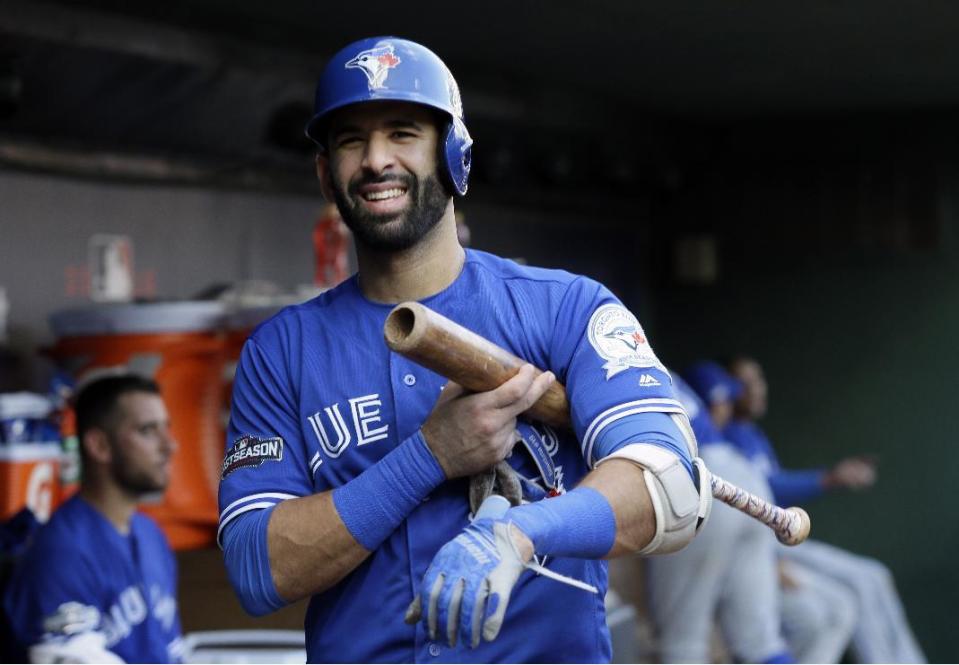 FILE - In this Oct. 6, 2016, file photo, Toronto Blue Jays' Jose Bautista smiles as he walks through the dugout during Game 1 of the team's American League Division Series against the Texas Rangers in Arlington, Texas. A person with knowledge of the negotiations tells The Associated Press that free agent outfielder Jose Bautista is staying with the Toronto Blue Jays after agreeing to an $18 million, one-year contract with mutual options for more years. (AP Photo/LM Otero, File)