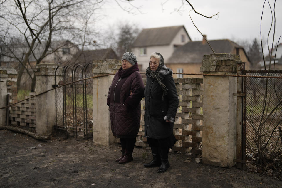 Anna Levchenko, 81, right, and a relative stand during a gathering to mark the first anniversary of the death of eight men killed by Russian forces in Bucha, Ukraine, Saturday, March 4, 2023. The eight had set up a roadblock on a road in the town in an attempt to prevent Russian troops from advancing, as they swept towards the Ukrainian capital at the start of their invasion. (AP Photo/Thibault Camus)